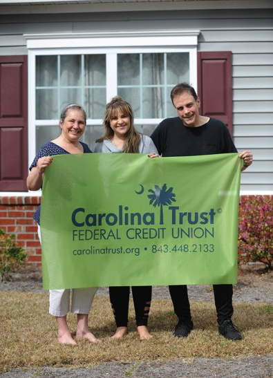 Boulavsky Family holding Carolina Trust Flag in front of their home
