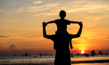 father and son on the beach during sunset