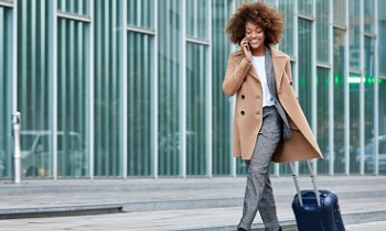 businesswoman with luggage smiling and talking on phone