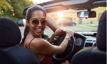 Young woman in her first car smiling and looking back at the camera
