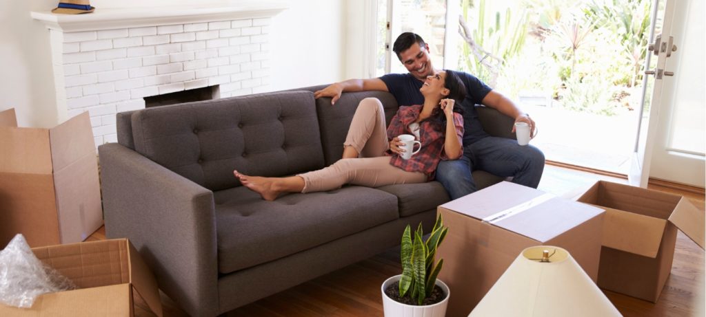 Couple sitting on couch while unpacking new home